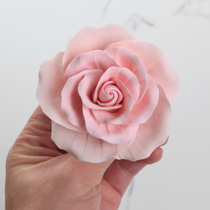 Close-up view of delicate handcrafted pink sugar rose petals with realistic garden rose blooming detail.