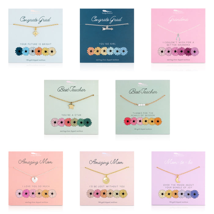 The image shows a collection of seven Lucky Feather necklaces, each displayed on a card with different sentiments such as 'Congrats Grad,' 'Best Teacher,' 'Amazing Mom,' and 'Mom-to-be'.