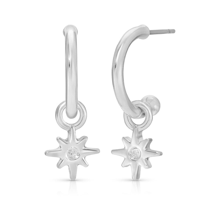A pair of silver hoop earrings with starburst charms hang against a white background.