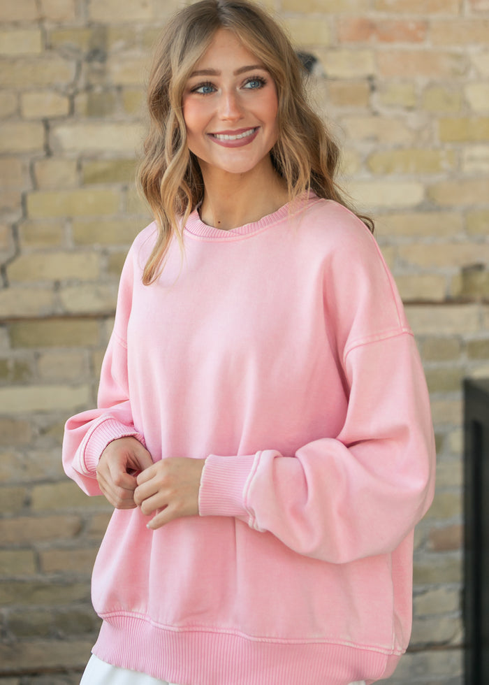 Oversized dusty pink fleece sweatshirt with dropped shoulders, styled with a white skirt.