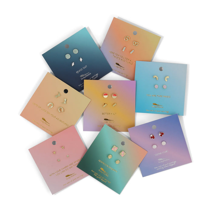 Several pairs of earrings attached to colorful gradient cards are arranged on a white surface.