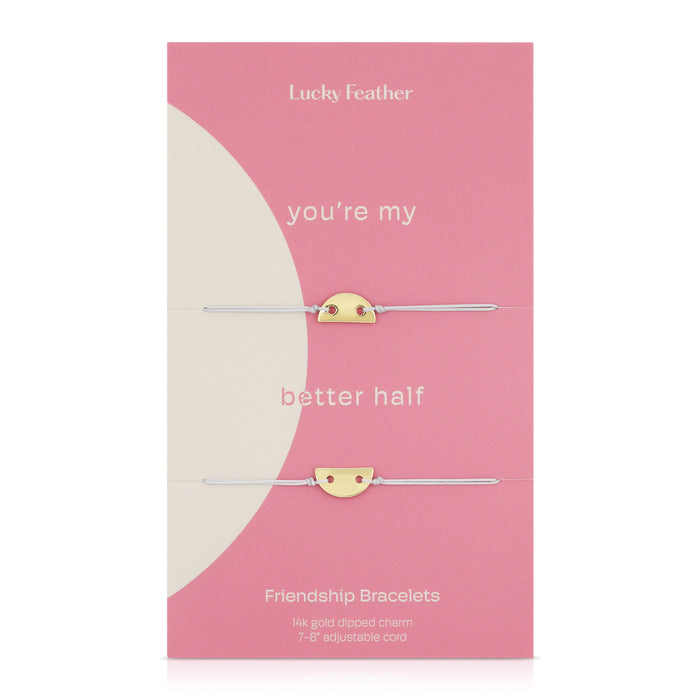 Two friendship bracelets with half-circle gold charms are displayed on a pink and white card labeled 'Lucky Feather.'