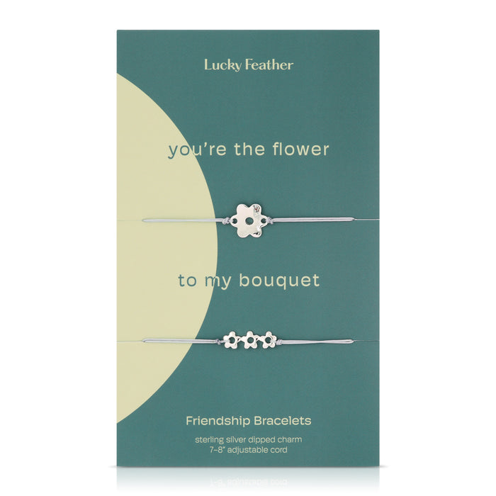 A teal and cream package featuring two silver flower charm friendship bracelets.
