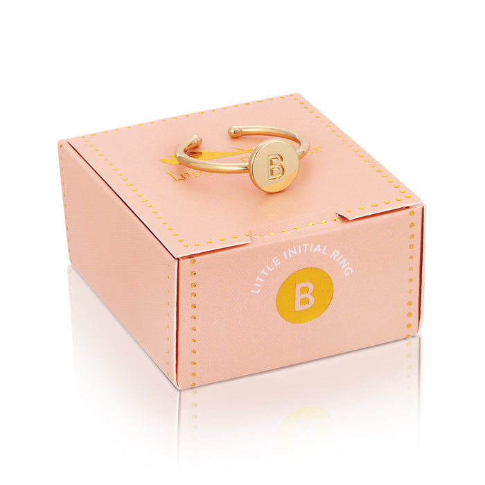 A gold-colored ring with the letter 'B' rests on top of a pink box with 'Little Initial Ring' printed on it.