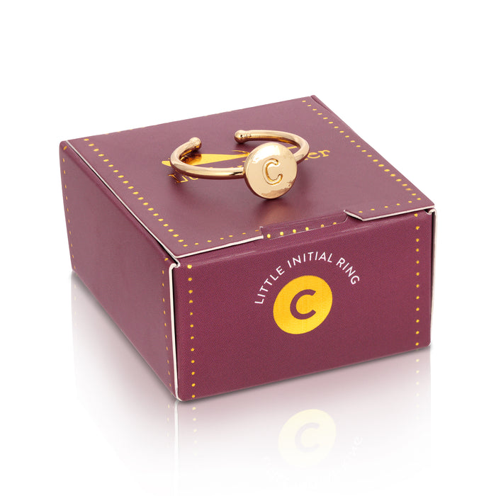 A gold ring with the letter 'C' rests on a purple box with the phrase 'LITTLE INITIAL RING.'