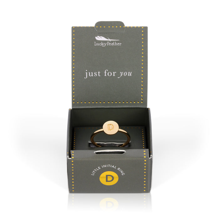 A gold ring with the letter 'D' on a round face, displayed in an open gray and gold gift box.