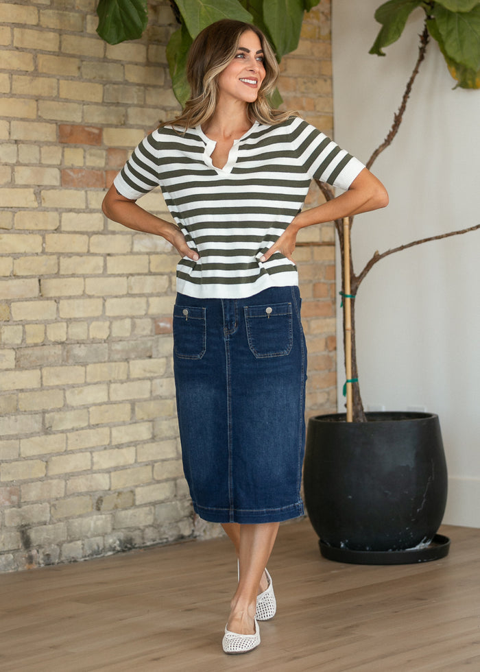 Striped knit top styled with a denim midi skirt and white woven flats.