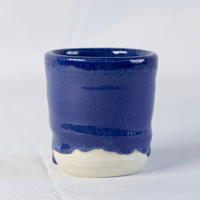 Cup in SP25 Dark Blue Mottled glaze, glossy cobalt blue with a wavy drip line above the unglazed white foot