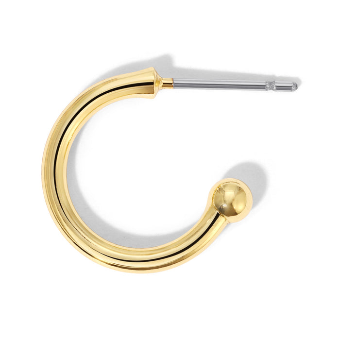 A golden hoop earring with a post is isolated on a white background.