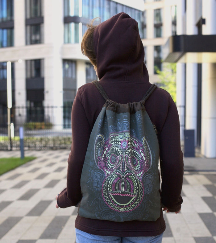 Tā Moko Drawstring Bag - Geometric face art with colorful patterns on khaki canvas by Symbolika
