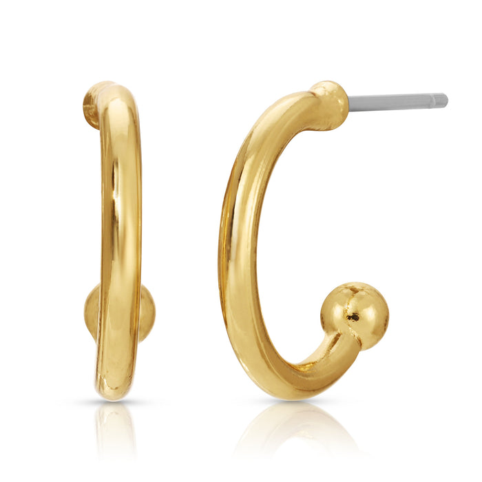 Two gold-colored hoop earrings, one turned to the side and one facing forward, sit on a white surface.