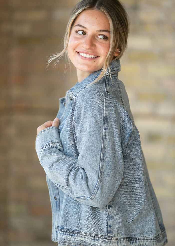 Light wash denim jacket shown from the side with relaxed sleeves and cropped hem.